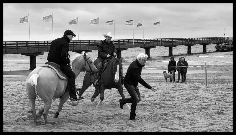 Zwei Reiter am Strand verfolgen einen Mann